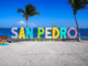 Colorful shops and golf carts along a sandy street in downtown San Pedro, Belize